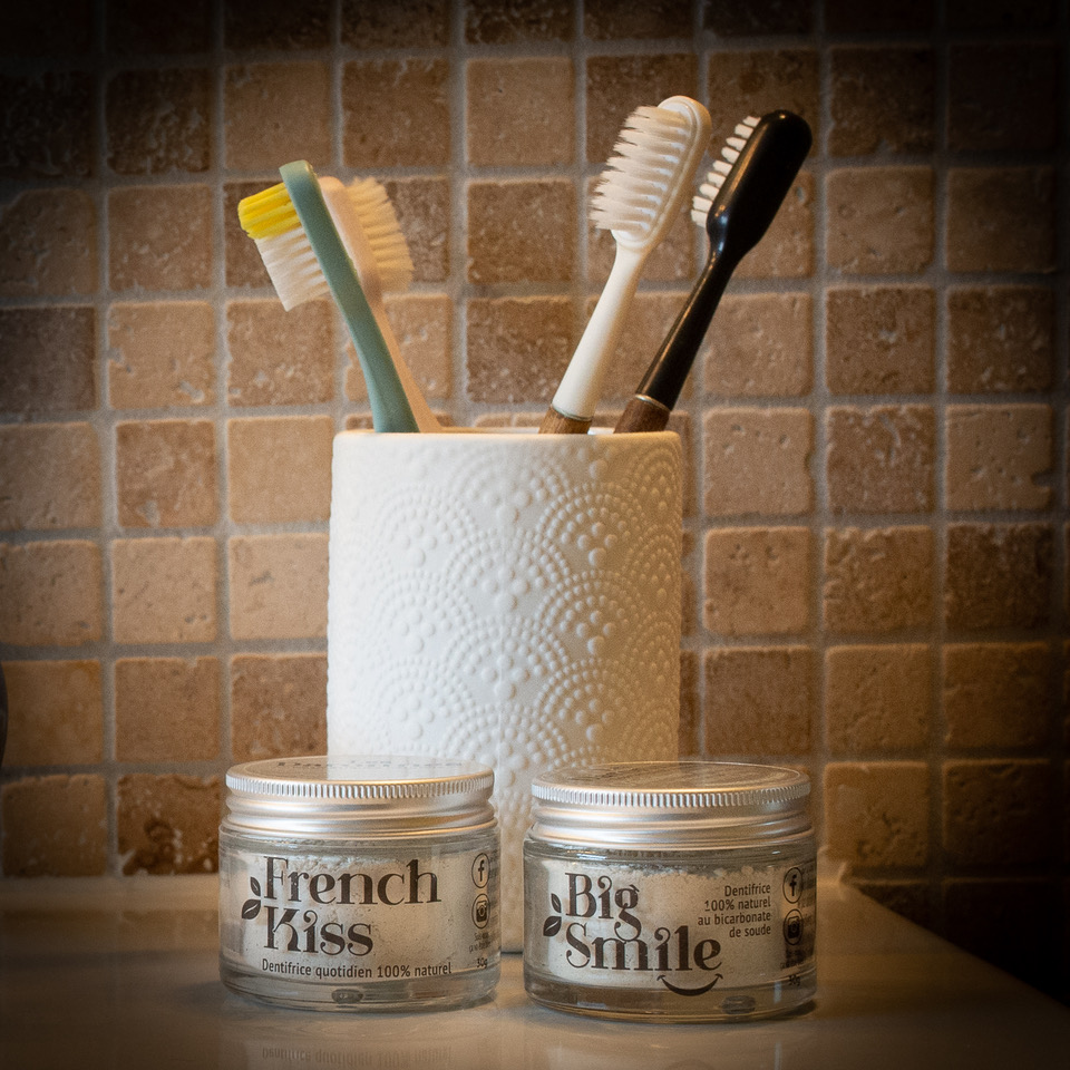 deux pots de dentifrice en poudre posés à côté d'un pot de brosses à dent