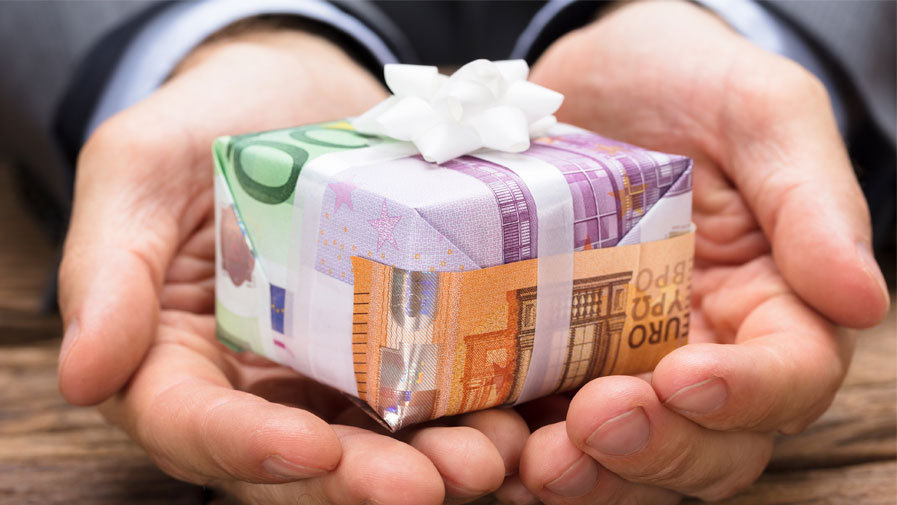 deux mains qui offrent un cadeau emballé dans des billets euros