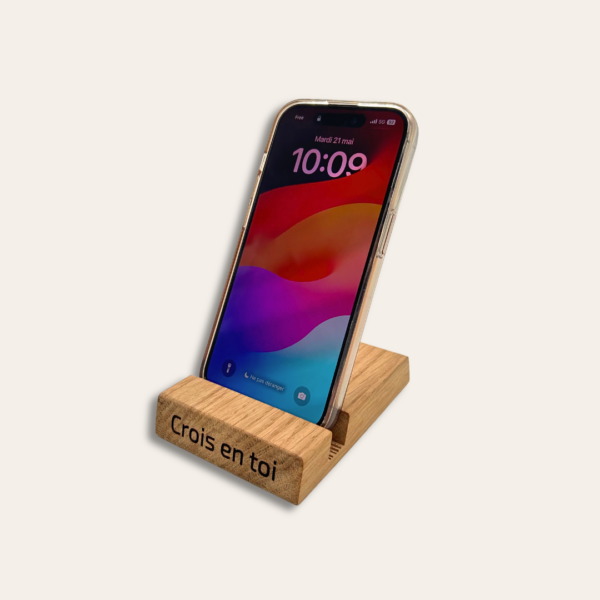 Support de téléphone en bois gravé avec un portable dessus.