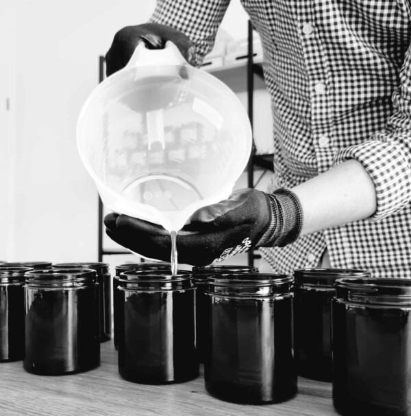 un homme verse un liquide dans des pots