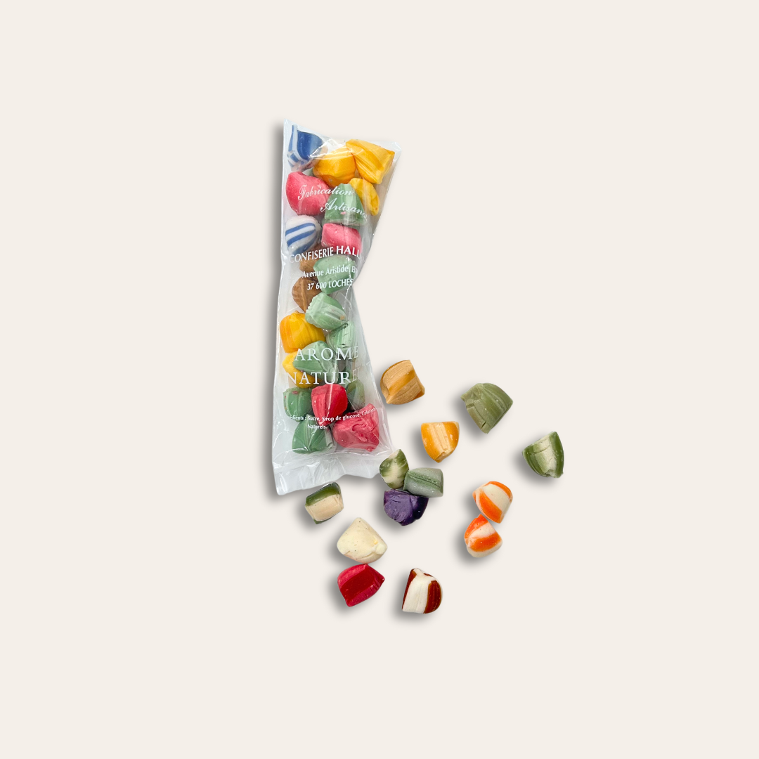 Berlingots artisanaux Berlingots toutes couleurs dans un sachet transparent et éparpillés.