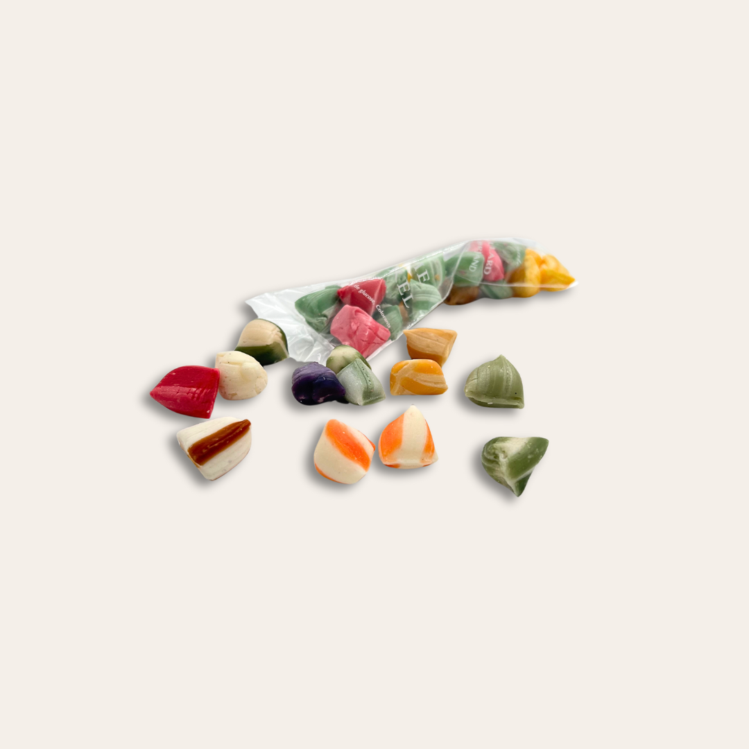 Berlingots personnalisés artisanaux Berlingots de toutes couleurs dans un sachet transparent et éparpillés.