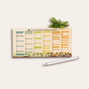 Petit calendrier en bois avec une plante en arrière-plan et un stylo en premier-plan.