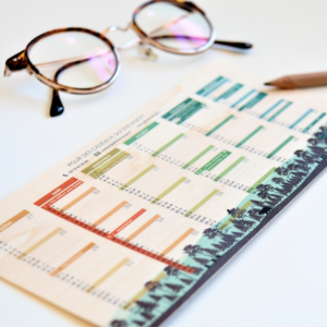 Petit calendrier en bois avec des lunettes et crayon sur le côté.