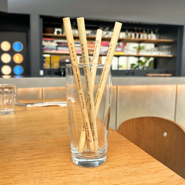 Pailles bambou dans un verre et posés sur une table de restaurant.