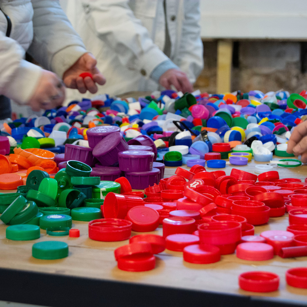 Plein de bouchons en plastique accompagnés de personnes qui les récupèrent.