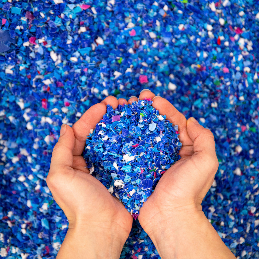 Débris de plastique écrasés et une main tenant ces morceaux au-dessus des débris.