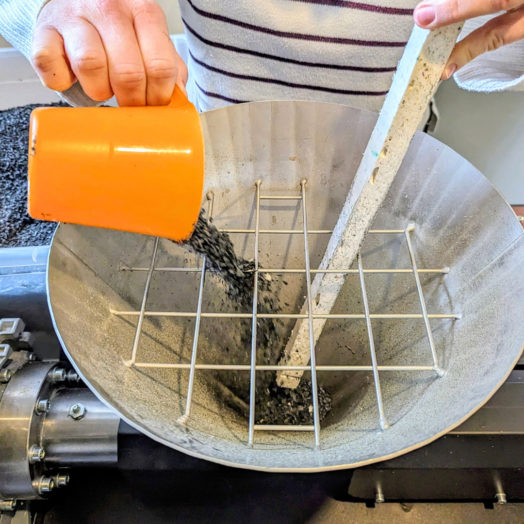 Homme versant des cailloux dans une machine.