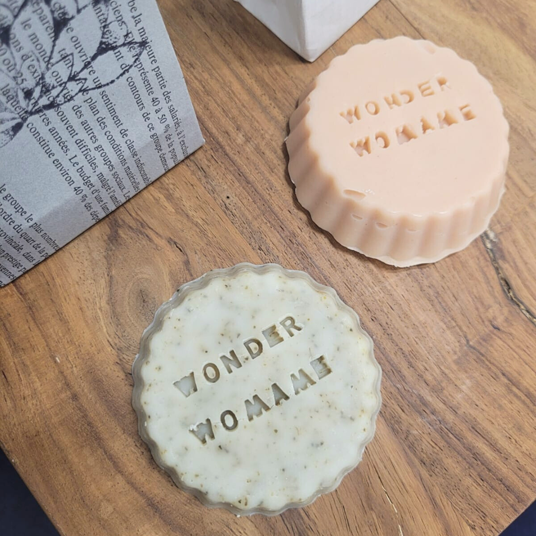 Savon bio moulé 60g artisanal Deux savons posés sur une table en bois et des mots sont gravés sur les savons, du papier en arrière-plan.