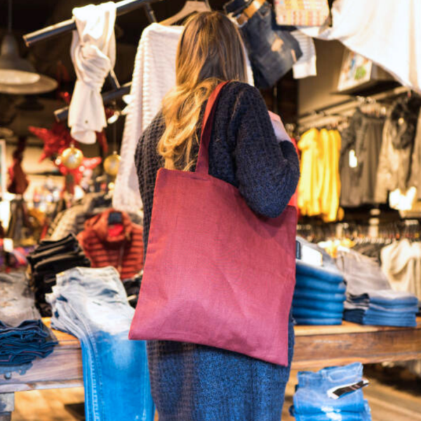 Femme portant un tote bag rouge dans un magasin de textiles.