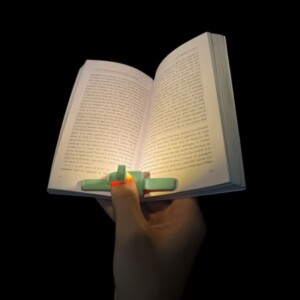 Lecture nocturne avec Lizia dame qui tient son livre d'une main et qui éclaire grâce à la lampe