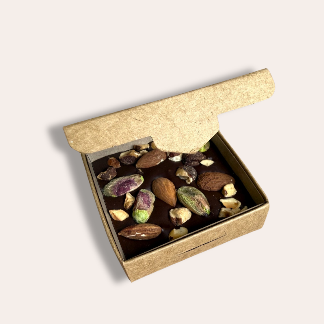 boîte kraft avec carré de chocolat mendiant à l'intérieur, avec pistaches amandes dessus