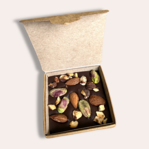boîte en kraft avec carré chocolat mendiants contenant des amandes, pistaches dessus ouverte entièrement